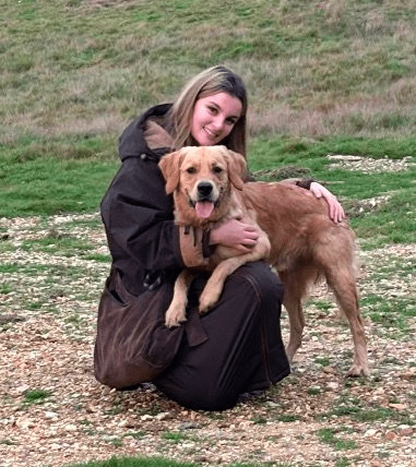 Young woman kneeling with golden retriever outdoors